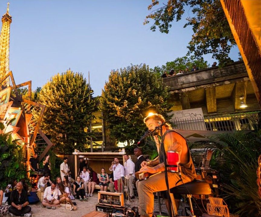 Musician playing to a seated crowd at dusk
